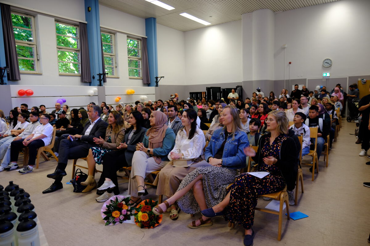 Gut gefüllte Aula mit Gästen bei der Einschulungsfeier
