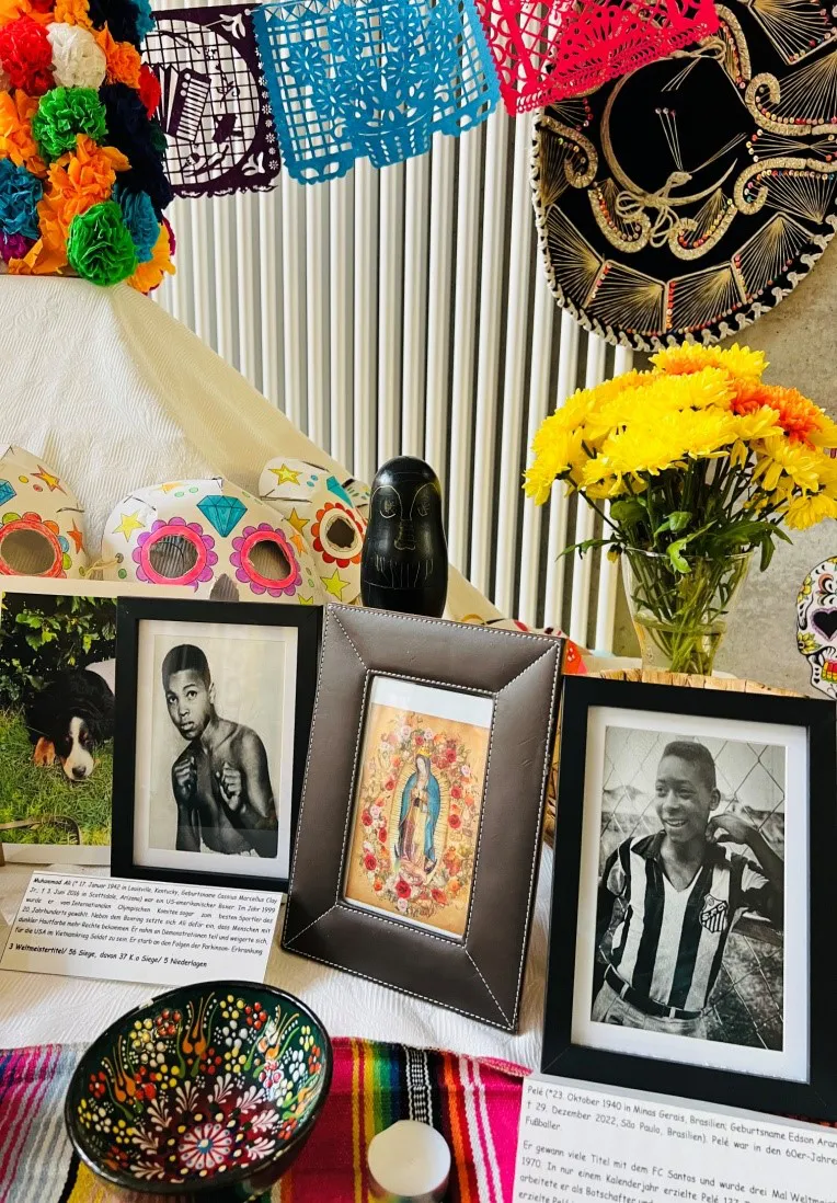 Gedenktisch zum Día de los Muertos mit gerahmten Fotos und Blumen