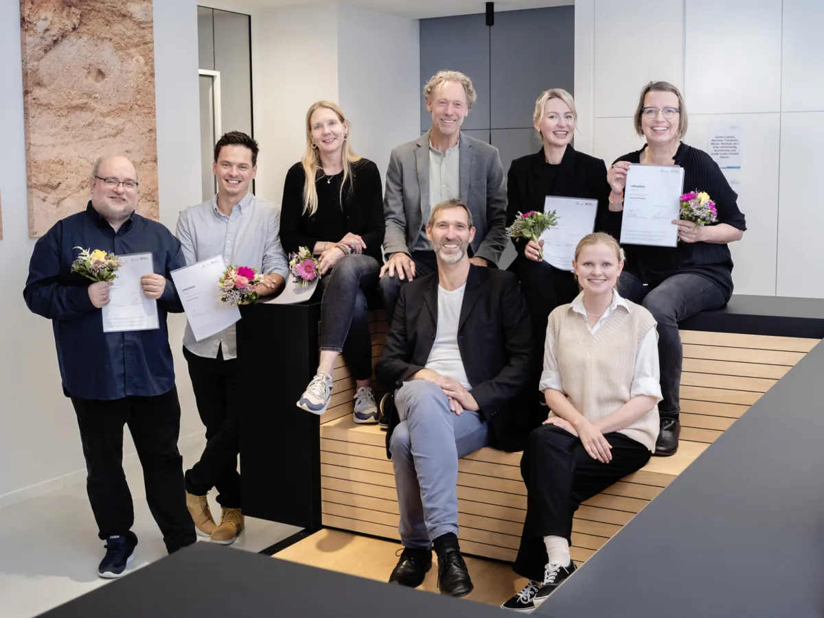 Gruppe mit Urkunden und Blumen bei einer Preisverleihung