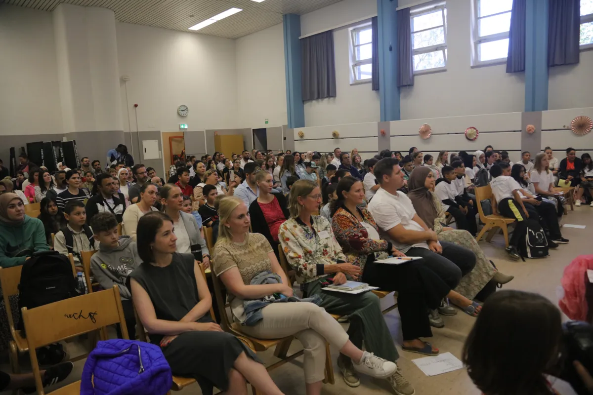 Gut gefüllte Aula mit Eltern und Gästen bei der Einschulungsfeier