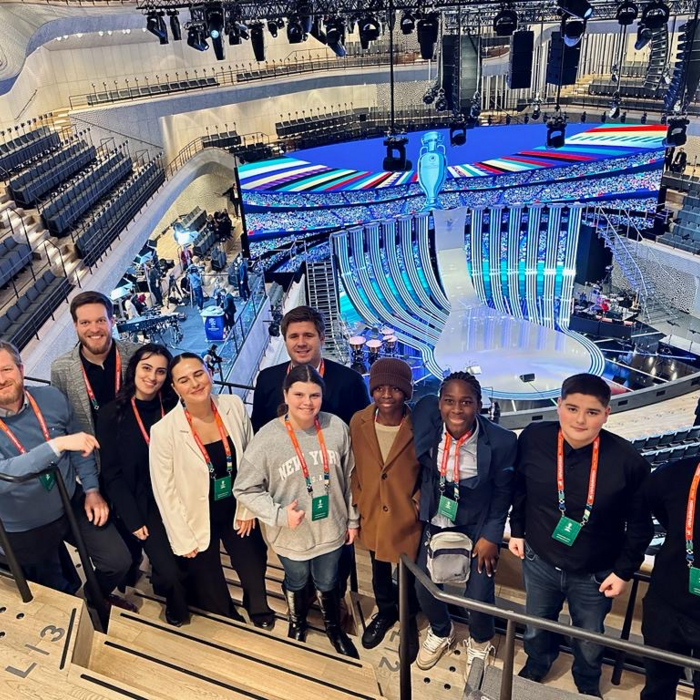 Eine Gruppe von Menschen steht in der Elbphilharmonie mit Blick auf eine Bühne mit bunten LED-Bildschirmen.