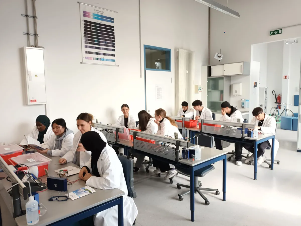 Schülerinnen und Schüler in Laborkitteln beim Experimentieren im Chemieraum