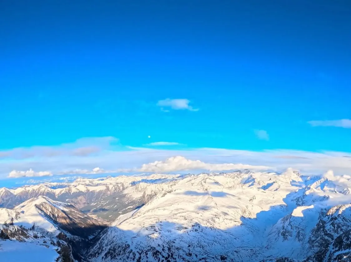 Blick über eine verschneite Berglandschaft unter blauem Himmel