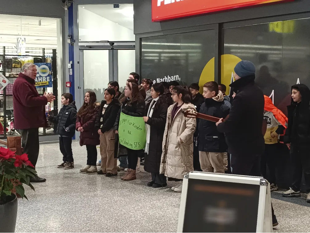 Schülergruppe mit Instrumenten und Plakaten bei einem Auftritt in einem Einkaufszentrum