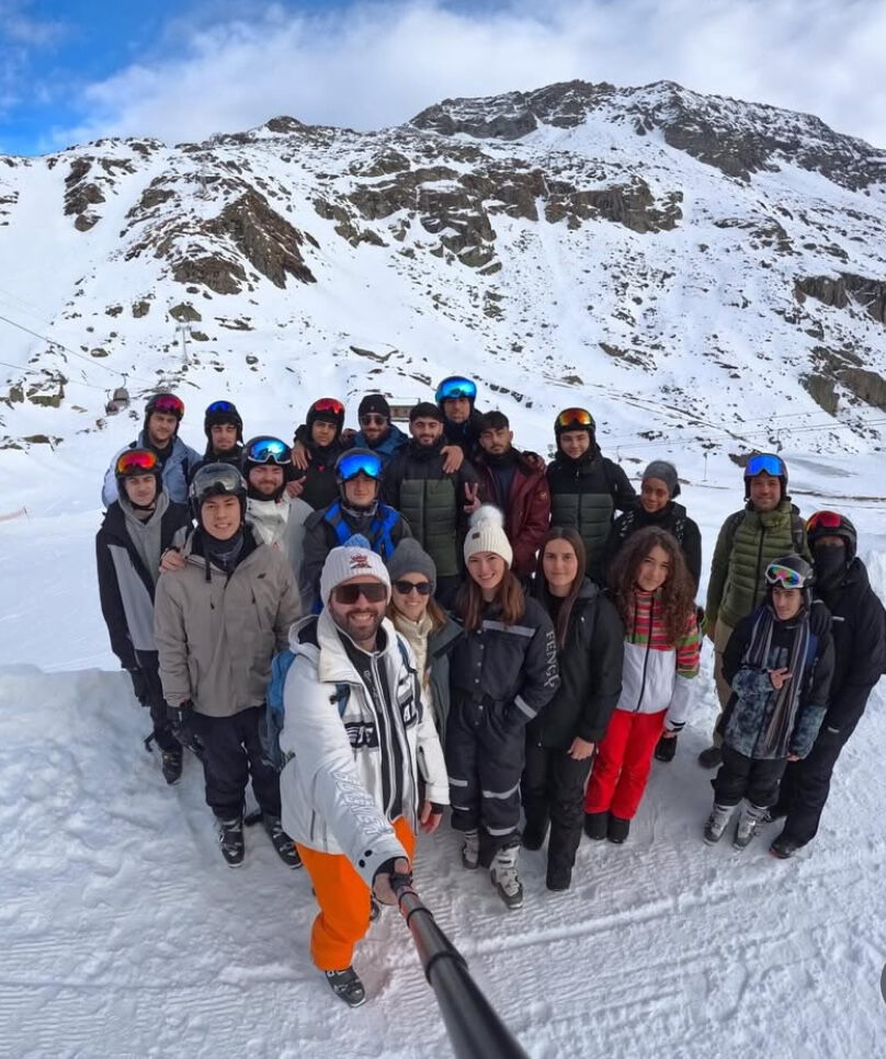 Schülergruppe in Winterkleidung auf einem verschneiten Berghang